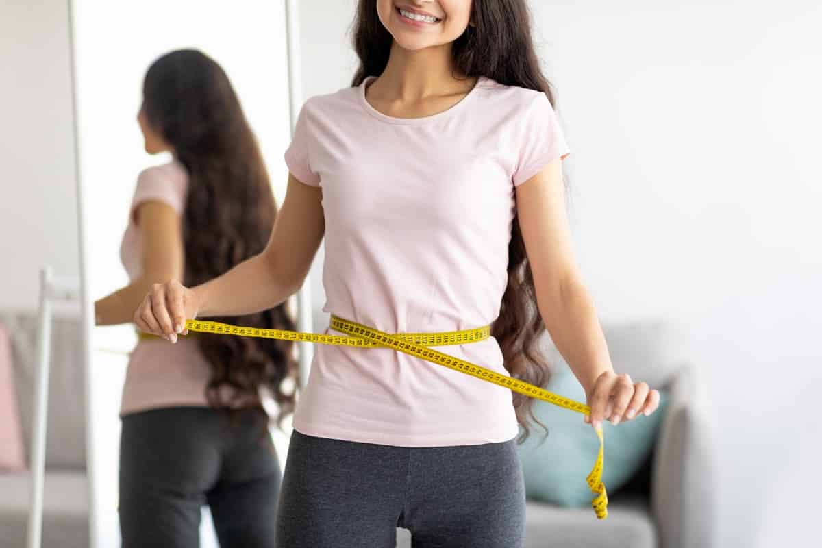 woman holding measuring tape around waist
