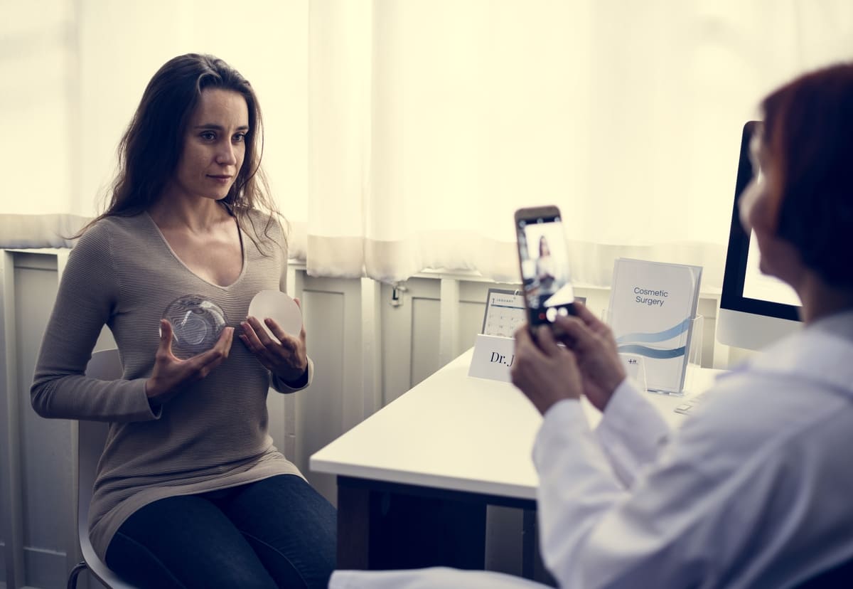 woman holding implants to chest thinking