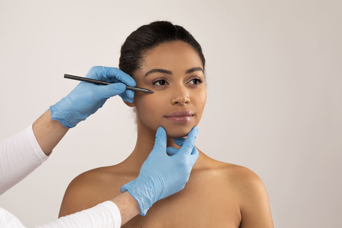 woman having lines drawn on face by plastic surgeon