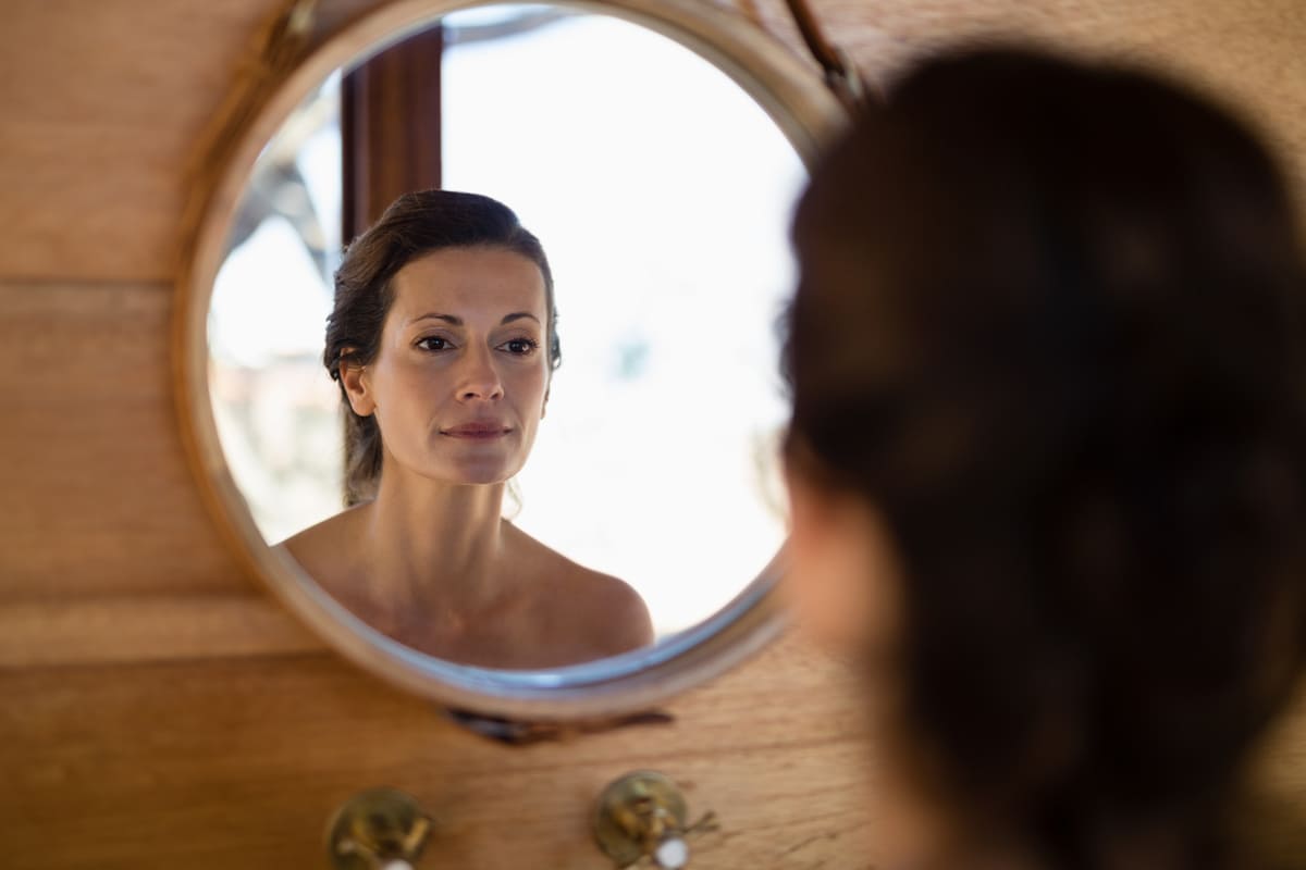 woman looking at face in mirror
